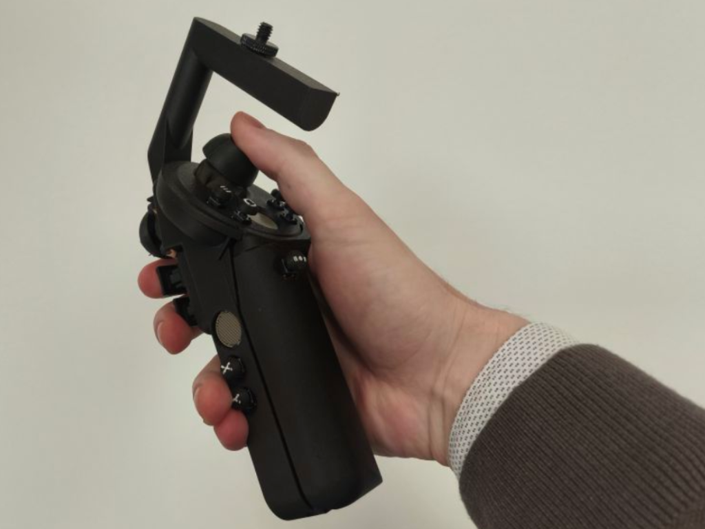 A black controller with buttons and joysticks  is held sideways in front of the camera.