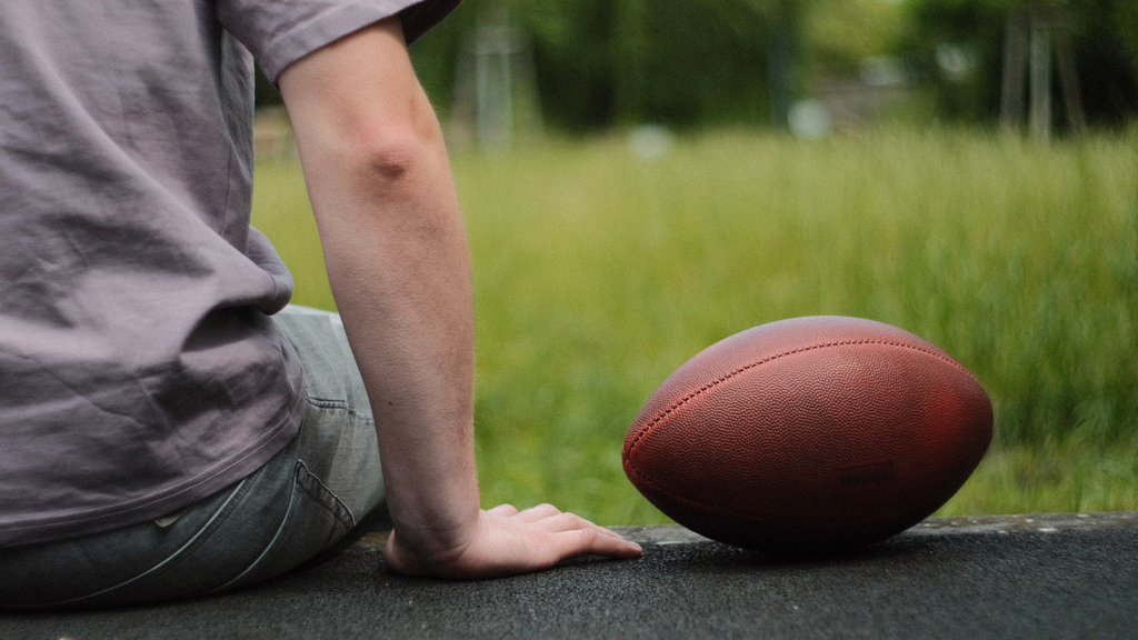 Person sitting next to an American football.