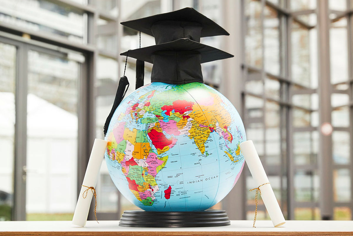 Two PhD hats on a globe.